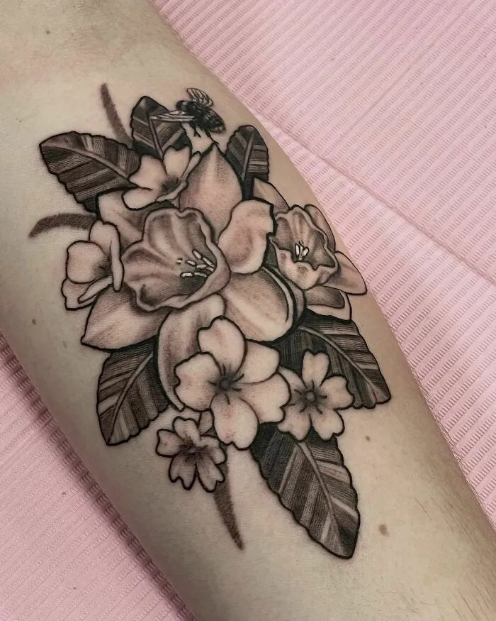Nature tattoo with floral design and bee on a person's arm.