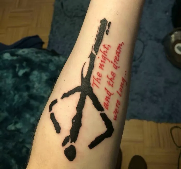 Creative word tattoo on forearm in black and red ink, featuring a quote.