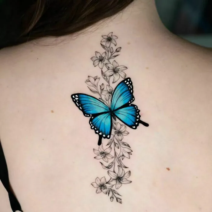 Blue butterfly and floral design nature tattoo on a person's back.