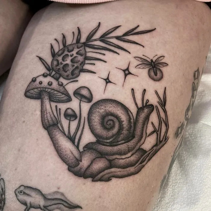 Nature tattoo with a snail and mushrooms, celebrating Mother Earth's wonders.