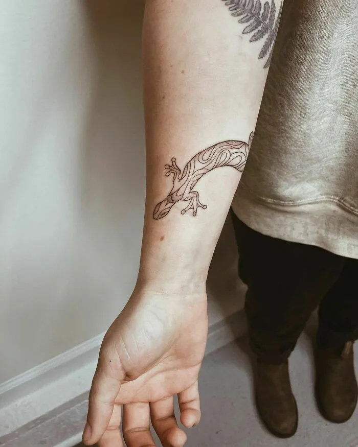 Nature tattoo of a stylized lizard on a person's forearm, showcasing earthy designs.