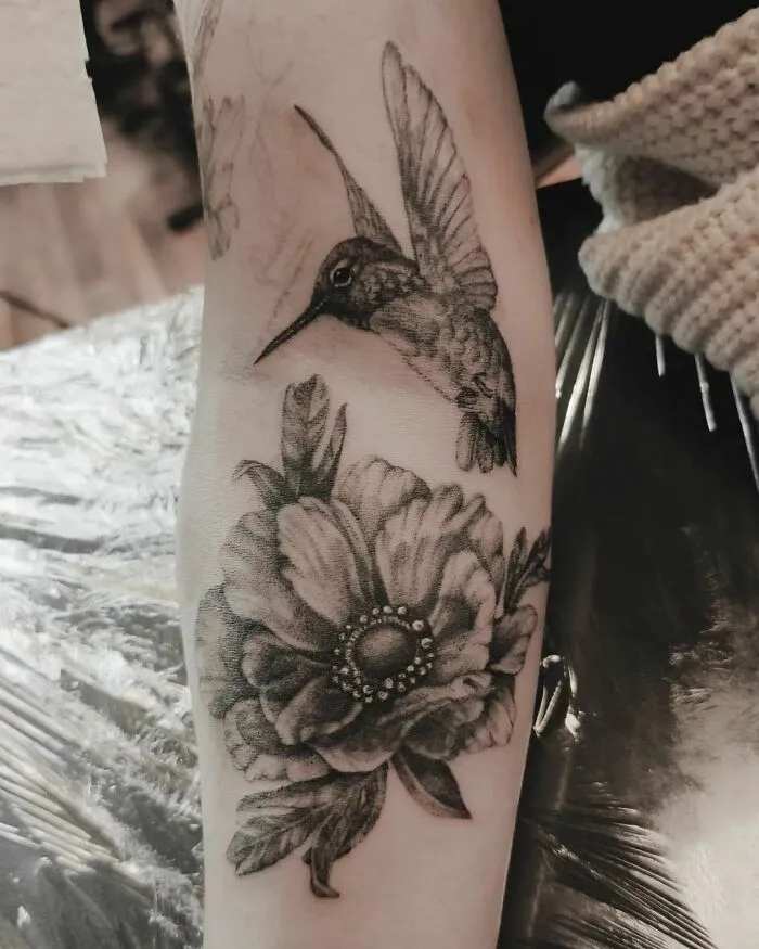 Nature tattoo featuring a detailed hummingbird and flower on a forearm, celebrating the beauty of Mother Earth.