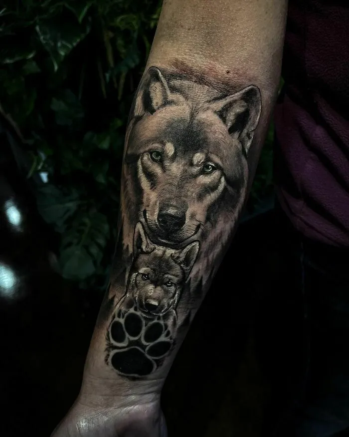 Wolf tattoo with paw print on forearm, embodying nature's wonders and the spirit of the wild.