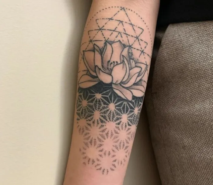 Geometric tattoo on forearm with lotus flower and intricate shapes, showcasing creativity and forms.
