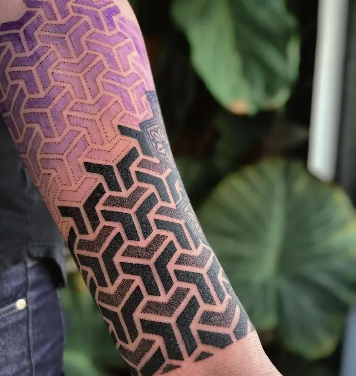 Arm with geometric tattoo, featuring intricate patterns and shapes in black and purple.