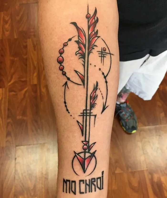 Arm tattoo with geometric designs and the text "MO CHROI," featuring abstract shapes in red and black.