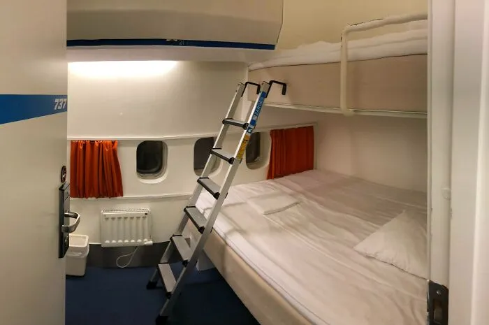 Airplane converted into a hotel room with bunk beds and a ladder, showcasing innovative building conversions.