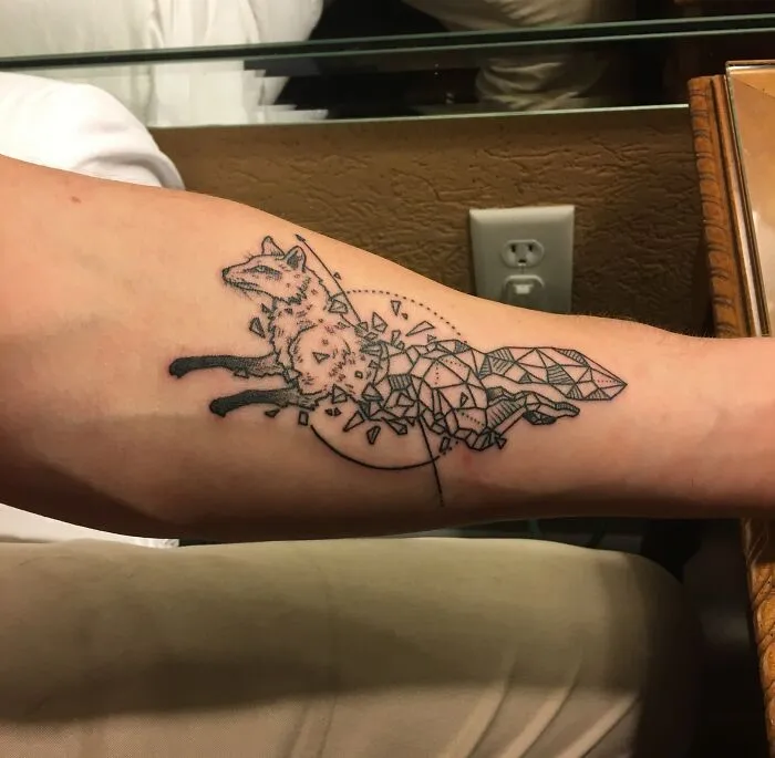 Geometric tattoo of a fox on a forearm, featuring intricate shapes and creative design elements.