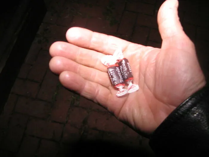 Hand holding a small wrapped candy, illustrating things the poor know but the rich don't in a viral thread.