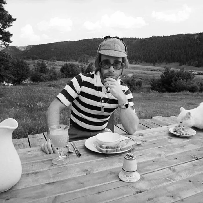 While British Star Elton John Posed For The Famous Photographer Terry O'neill, A Cat Stole The Show With Its Snack. Colorado, United States. 1974