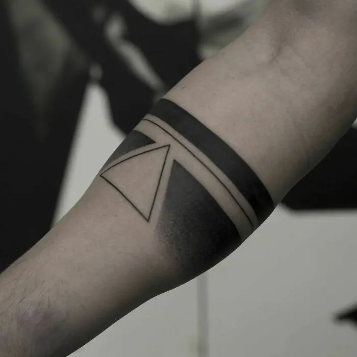 Geometric tattoo design on forearm, featuring a triangle and bold black bands.