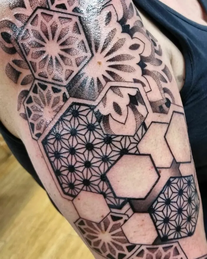 Geometric tattoo featuring intricate shapes and forms on an arm, showcasing creative design elements.
