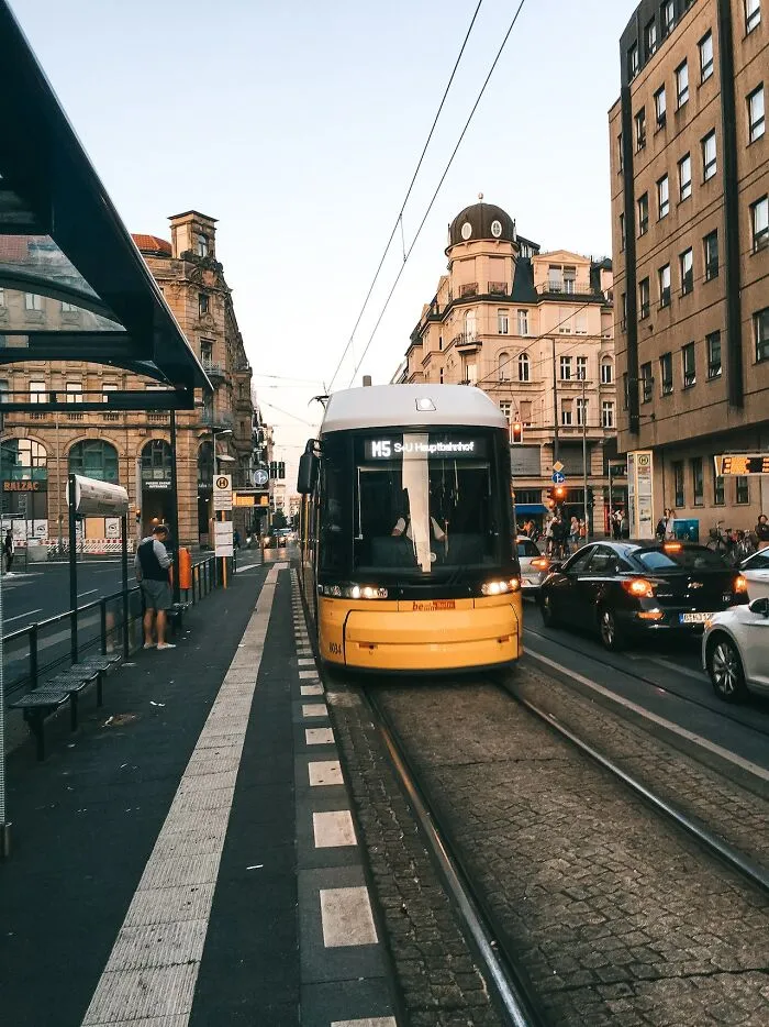 Yellow tram on city street with passengers, illustrating everyday scenes the poor know but the rich don't experience.