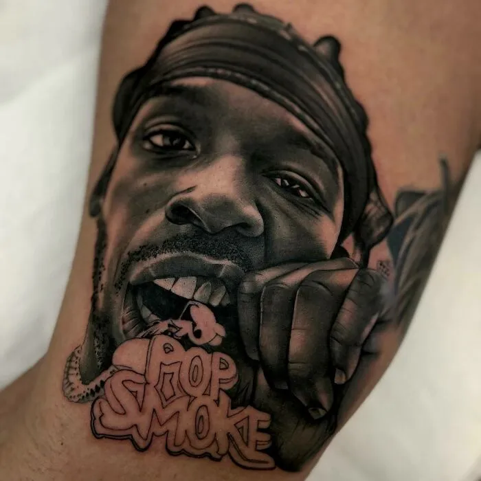 Super realistic tattoo of a black man's face with "Pop Smoke" lettering, showcasing intricate detailing.