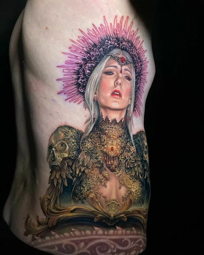 Colorful, realistic tattoo of a regal woman with intricate detailing and a pink headdress on the side of the body.