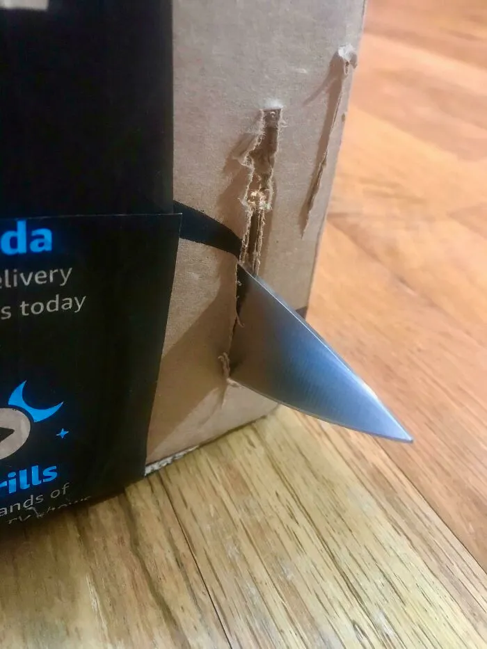 Para obtener esta foto, quité la funda de seguridad, el protector de la punta y los amarres y, luego, forcé este cuchillo de chef Wüsthof de 8 pulgadas a través de una caja de Amazon