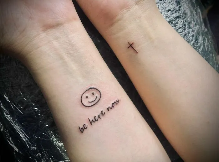 Creative word tattoos with smiley face and "be here now" text on forearms for inspiration.