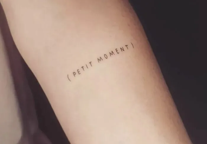 Minimalist word tattoo with "Petit Moment" inked on an arm, showcasing creative word tattoos for inkspiration.