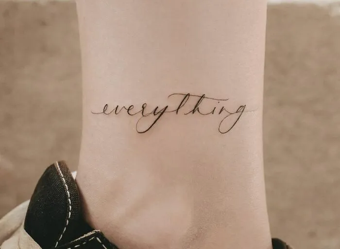 Word tattoos on wrist displaying the word "everything" in elegant script.