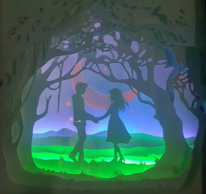 boy and girl made out of paper holding by their hands under the tree