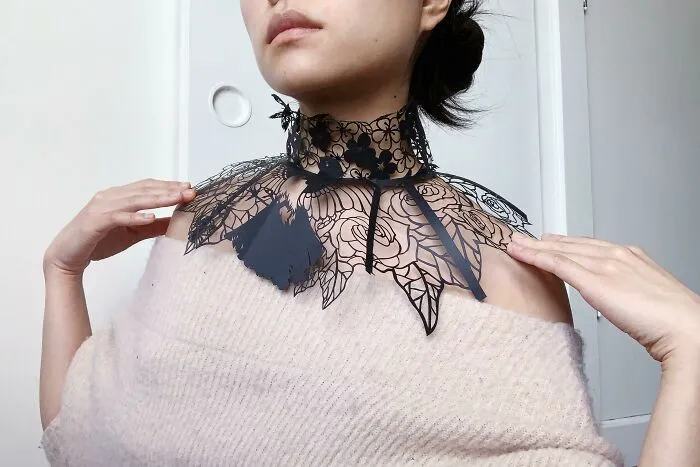 a black collar made out of the paper on the woman's neck