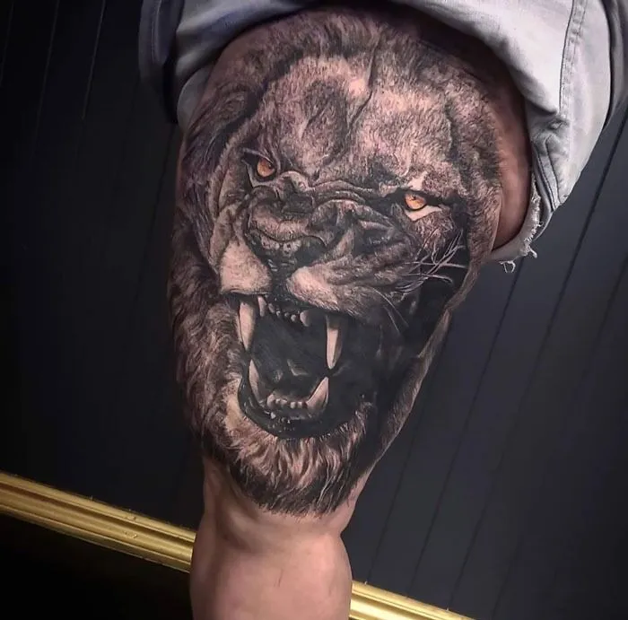 Realistic lion tattoo on thigh showcasing both simplicity and intricate detail in the design.