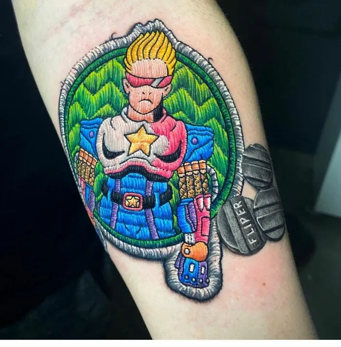 Tattoo showing a colorful embroidered-style superhero, showcasing Eduardo Lozano's new dimension in tattooing.