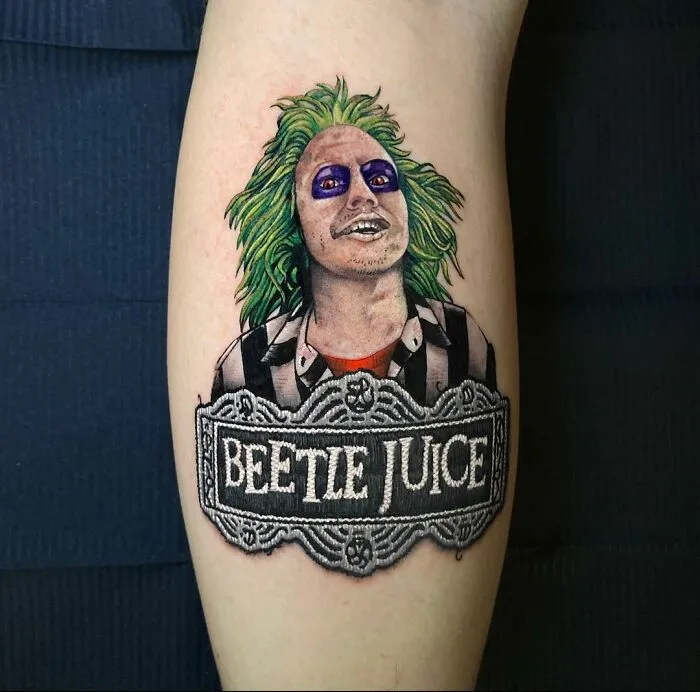 Tattoo of a character with green hair and striped suit, inked by Eduardo Lozano, showcasing a new dimension in tattooing.
