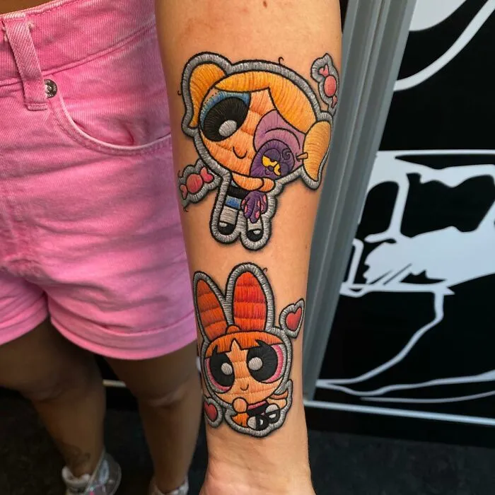 Tattoo by Eduardo Lozano featuring colorful cartoon characters on a person's forearm.
