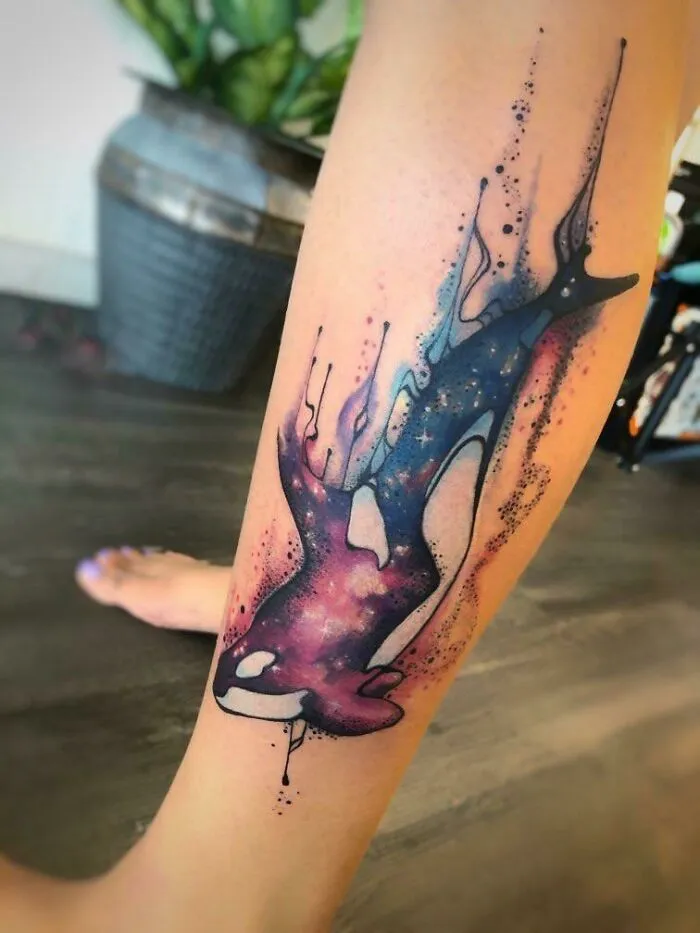 Astrology-themed space tattoo with a cosmic whale design on leg.