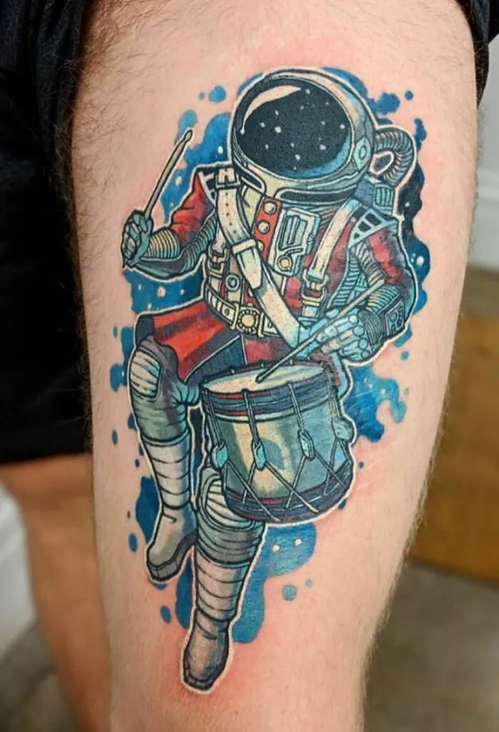 Astronaut playing drums tattoo, vibrant colors, perfect for astrology fans.