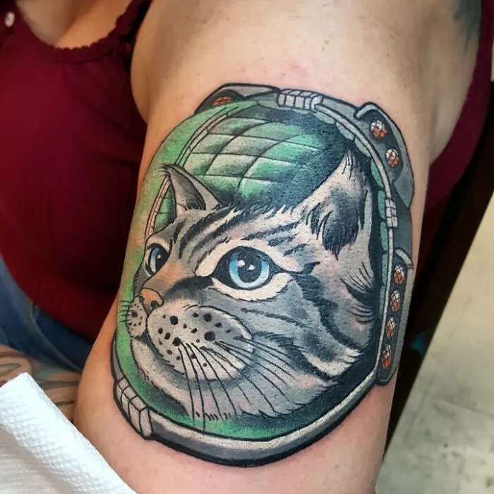 Tattoo of a cat in an astronaut helmet on a person's arm, perfect for astrology enthusiasts.