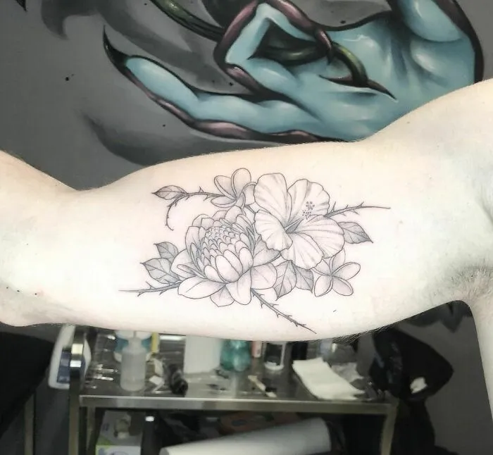 Elegant flower tattoo design on a person's arm, showcasing detailed blooms and leaves.