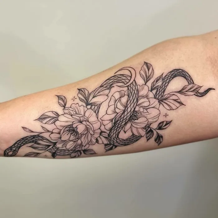 Flower tattoo design featuring intricate blossoms and flowing ribbons on forearm, showcasing elegance and beauty.
