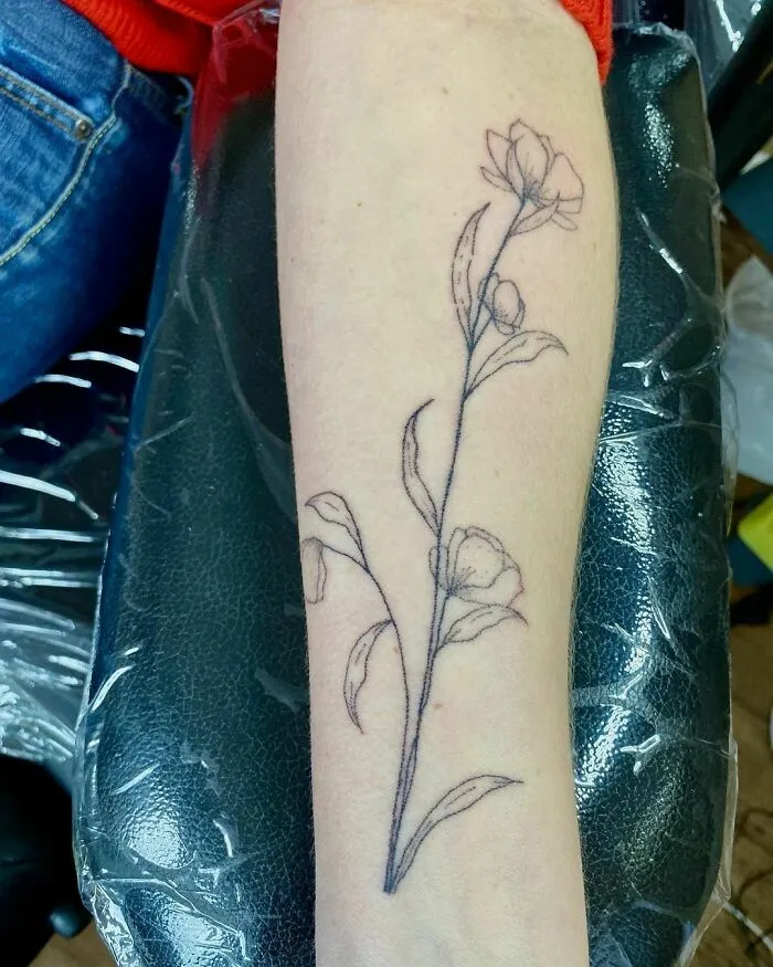 Minimalist flower tattoo on forearm, showcasing elegance and beauty.