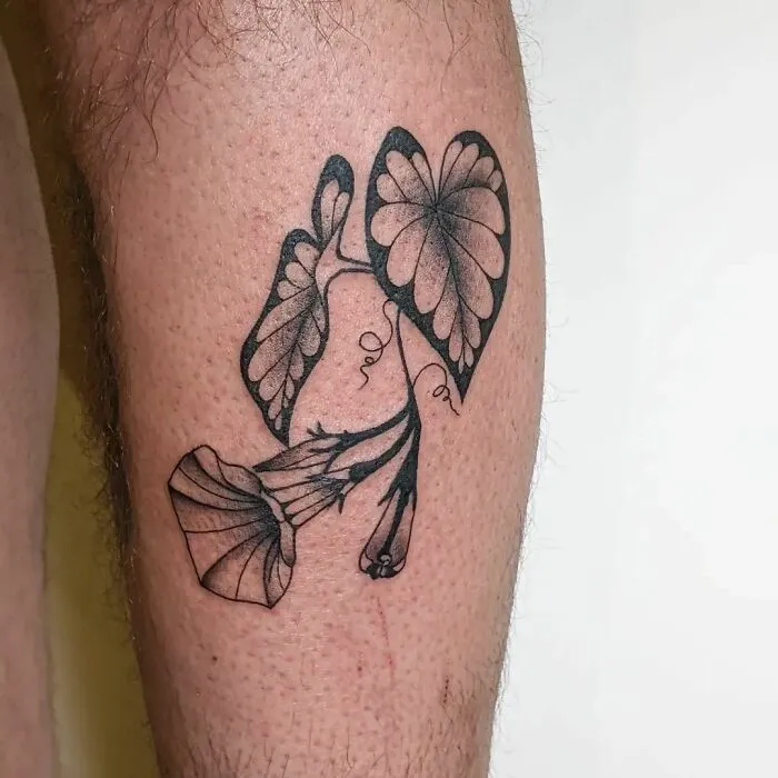 Floral tattoo on leg featuring elegant black ink design with intricate petal details.