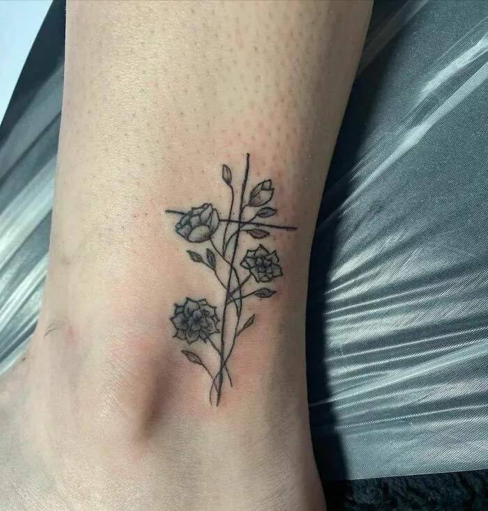 Delicate flower tattoo on ankle, showcasing elegance and beauty with a minimalist design.