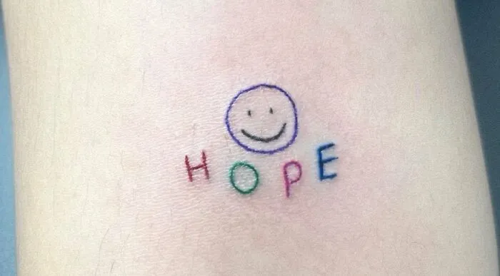 “Hope” Lettering Tattoo with a Smile Emoji
