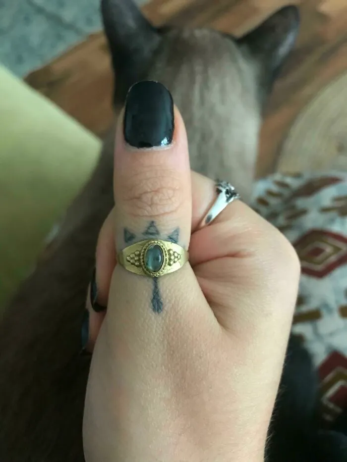 Tattoo matched with a ring, cat's ears in the background.