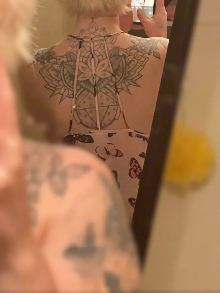 Back tattoo perfectly aligned with dress pattern in mirror selfie.