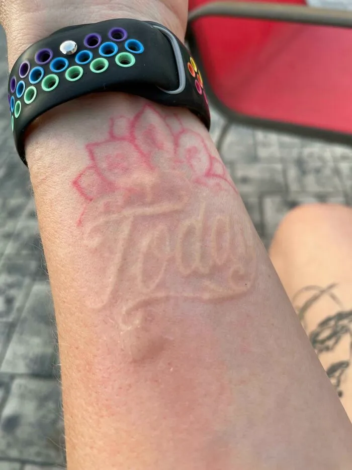 Tattoo with the word "Today" blends perfectly with the situation, beneath a rainbow-colored watch band.