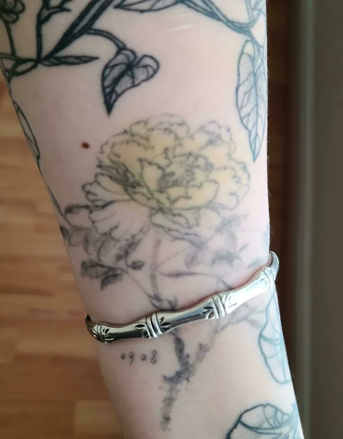 Floral tattoo seamlessly aligns with a silver bracelet, showcasing a perfect match with the situation.