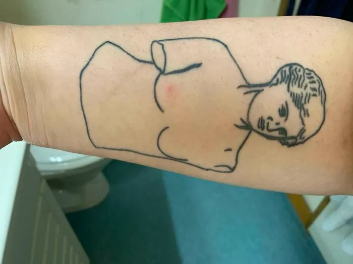 Tattoo of a statue outline on arm, humorously aligning with a bruise spot.