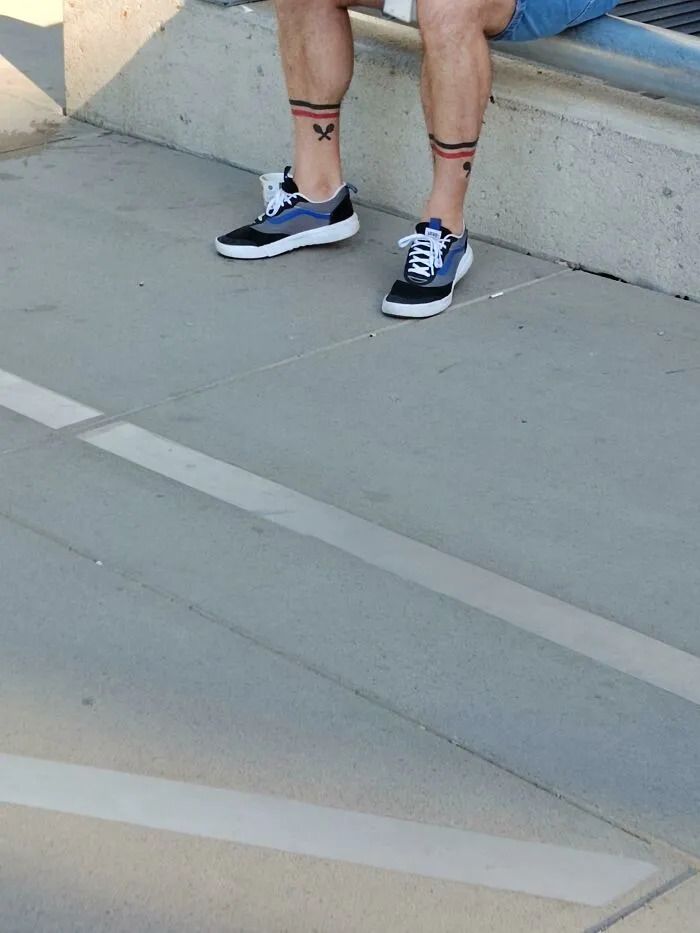 Tattoos matching perfectly with shoe patterns on a person's legs sitting on a bench.