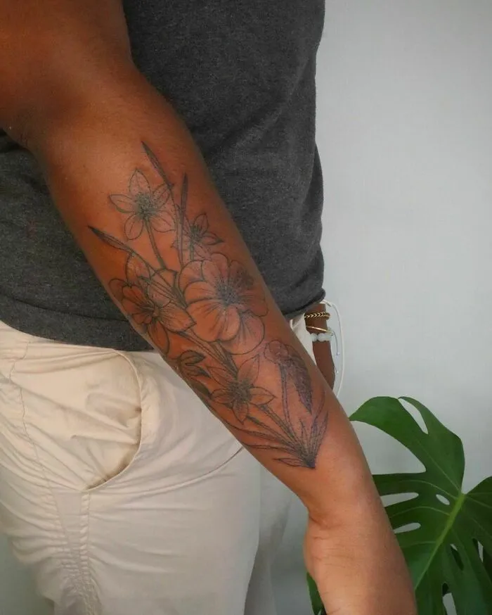 Floral tattoo on forearm radiating elegance and beauty, featuring detailed flower designs in black ink.