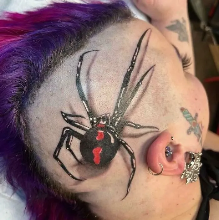 Realistic spider tattoo on head, showcasing intricate detailing and artistry.