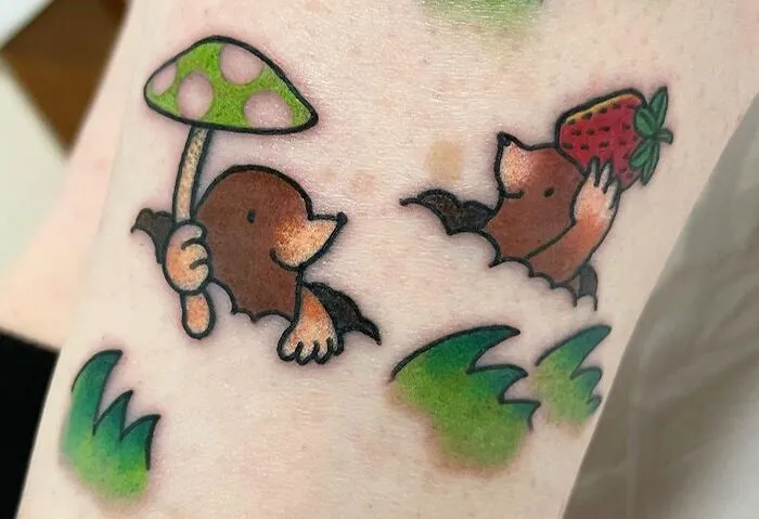 Cute animal tattoos of moles holding a mushroom and strawberry, celebrating the animal kingdom.