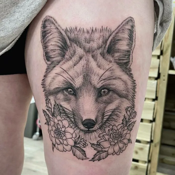 Animal tattoo of a fox with flowers, showcasing detailed line work and shading.