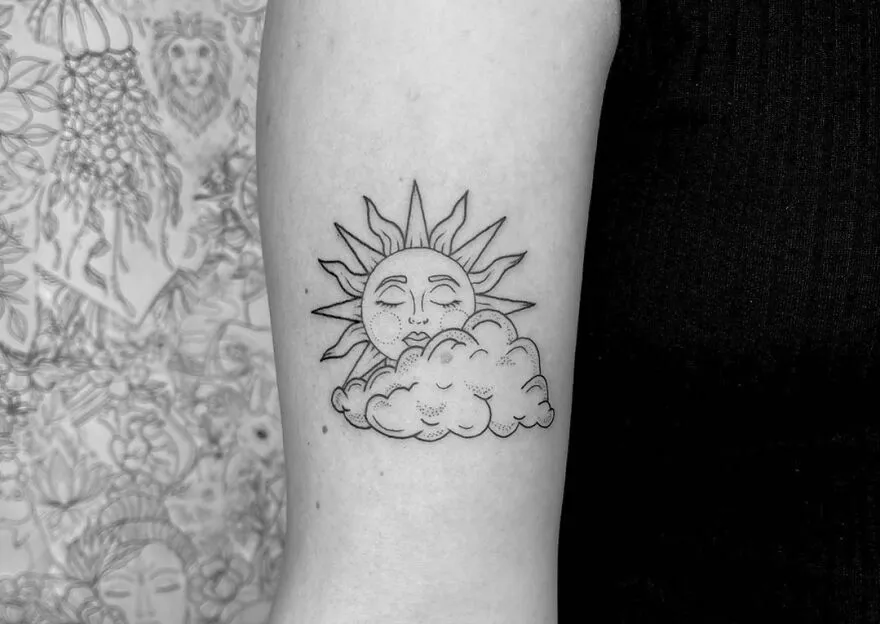 Outer space tattoo with a sun and cloud design on forearm, showcasing celestial artistry.