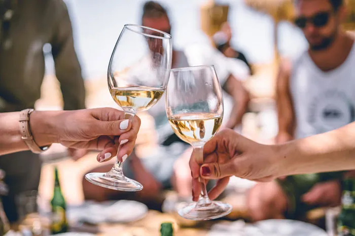 Two people clink white wine glasses